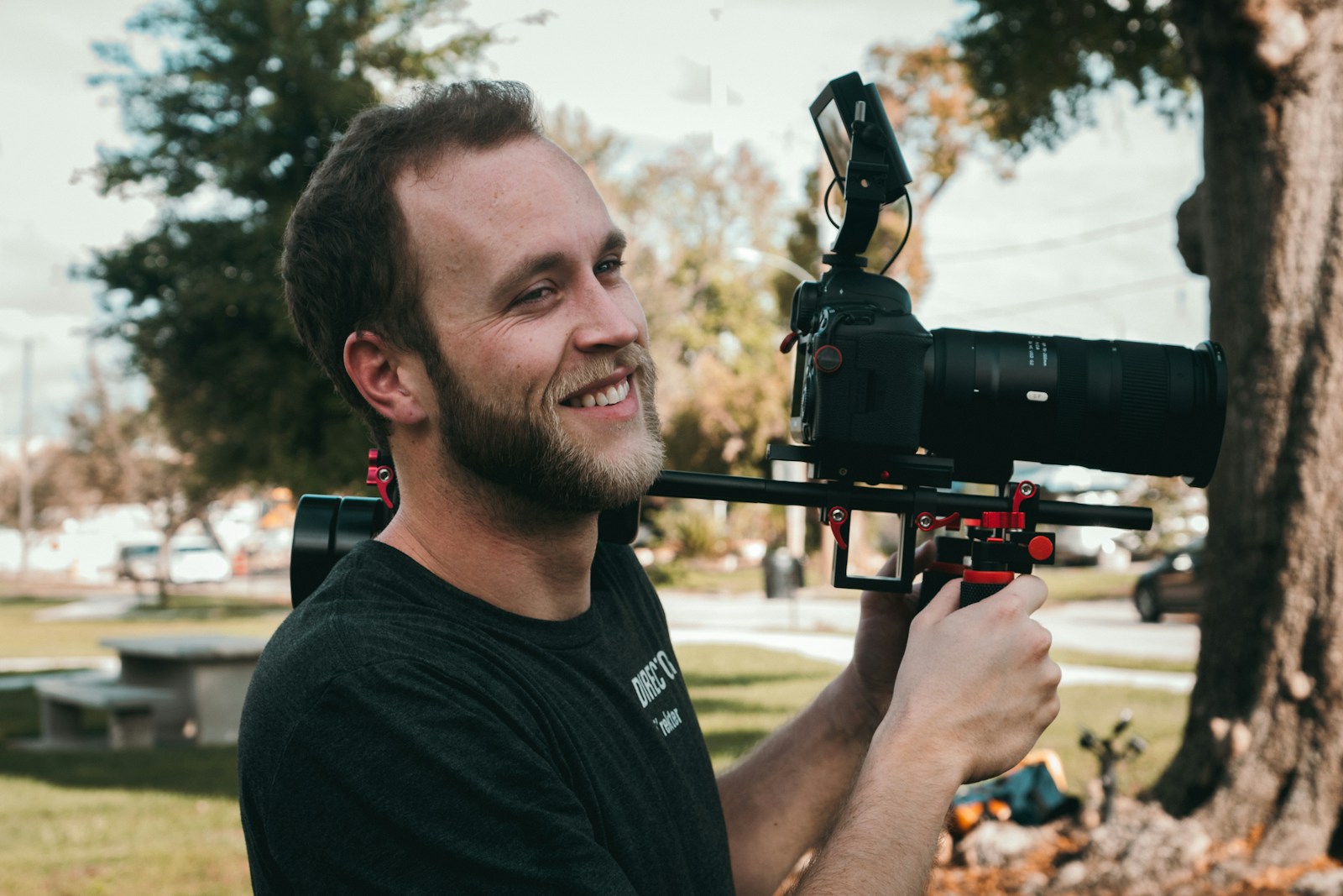 man smiling standing near the DSLR camera