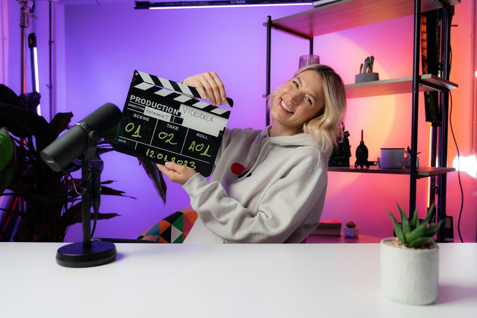 a woman sitting at a table holding a movie clapper